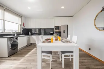 a white kitchen with a white table and chairs at Casa das Raposinhas VII in Funchal