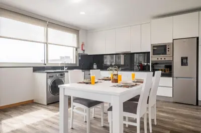 a white kitchen with a white table and chairs at Casa das Raposinhas VII in Funchal