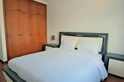 a bedroom with a white bed and a wooden cabinet at MG Hollidays in Funchal
