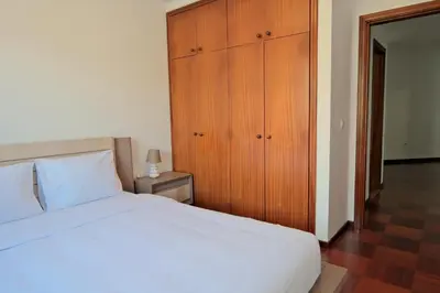 a bedroom with a white bed and a wooden cabinet at MG Hollidays in Funchal