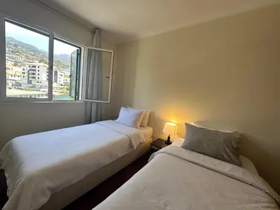 a bedroom with a bed with white sheets and a window at Aqua City Center in Funchal