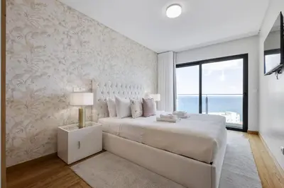 a white bedroom with a large bed and a window at The Ocean Gaze by Homie in Funchal