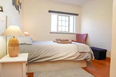 a bedroom with a bed with a lamp and a chair at Rosária Flat in Santa Cruz
