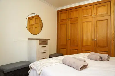 a bedroom with a bed with wooden cabinets and a mirror at Rosária Flat in Santa Cruz