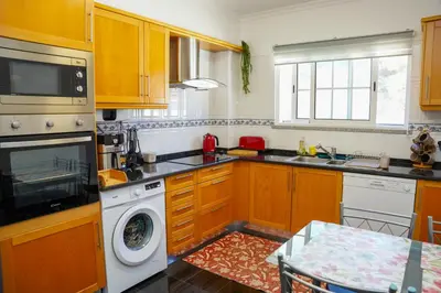 a kitchen with wooden cabinets and a washing machine at Rosária Flat in Santa Cruz
