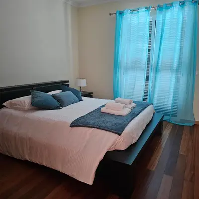 a bedroom with a large bed with blue curtains at Jose & Idalina House in Funchal