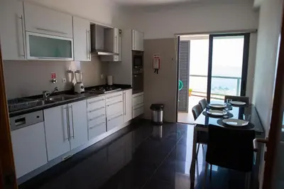 a kitchen with white cabinets and a table and a window at Moradia Garcês in Santa Cruz