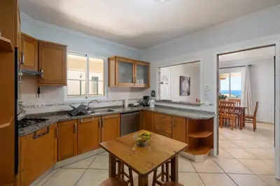 a kitchen with wooden cabinets and a wooden table at Gazela House Comfort & Barbecue in Porto Santo in Porto Santo