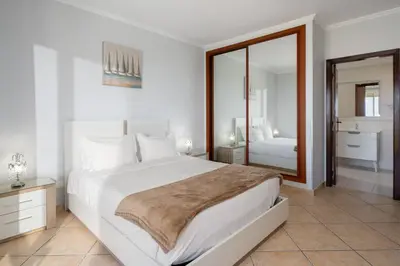 a white bedroom with a large bed and a mirror at Gazela House Comfort & Barbecue in Porto Santo in Porto Santo