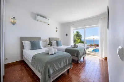 a bedroom with two beds and a view of the ocean at Casa Maresia da Salema in Salema