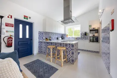 a white bedroom with a large bed and a large window at Casa Maresia da Salema in Salema