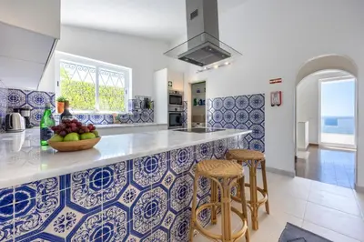 a patio with a table with an umbrella and the ocean at Casa Maresia da Salema in Salema