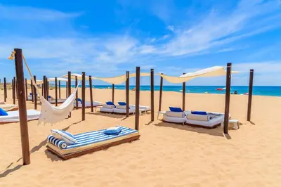 a beach with chairs and hammocks on the sand at Casa Maresia da Salema in Salema