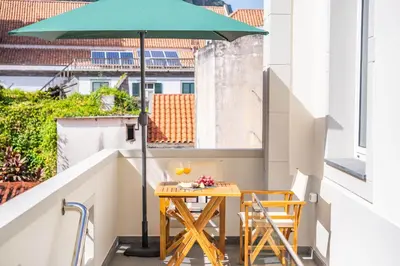 a table and chairs on a balcony with an umbrella at Nati by KAAMAH in Ribeira Brava