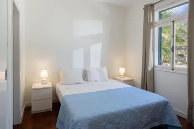 a white bedroom with a bed and two lamps at Vivenda do Moinho Refuge in Porto Santo in Porto Santo