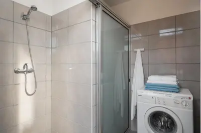 a bathroom with a washing machine and a shower at Vivenda do Moinho Refuge in Porto Santo in Porto Santo