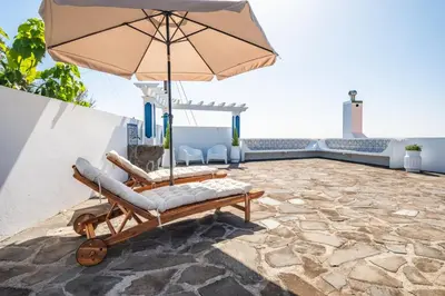 a chair and an umbrella on a patio at Blue House - By WehostMadeira in Ponta do Sol