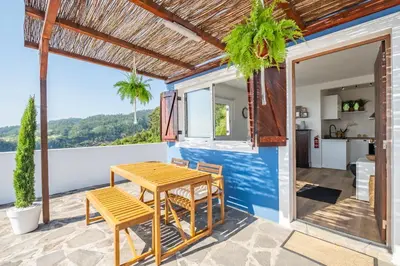 a patio with a wooden table and chairs and a kitchen at Blue House - By WehostMadeira in Ponta do Sol