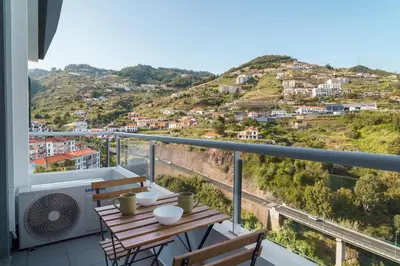 a balcony with a table and chairs and a mountain at GuestReady - Calm Haven in Madeira in Caniço