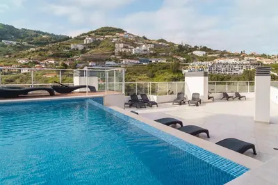 a swimming pool on top of a building with a mountain at GuestReady - Calm Haven in Madeira in Caniço