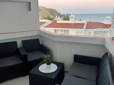 a balcony with two chairs and a table with a plant at Sunrise Luz Apartament in Luz