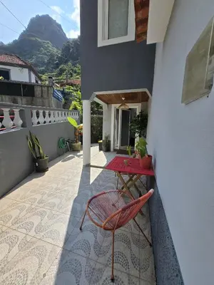 a patio with a red table and chairs on a balcony at Family House in Campanário