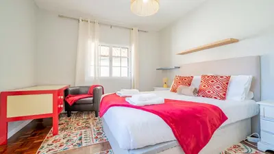 a bedroom with a bed with a red blanket and a chair at Family House in Campanário