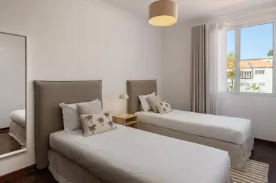 two beds in a white room with a window at Quebra Costas I by An Island Apart in Funchal