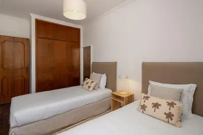 a bedroom with two beds and a wooden cabinet at Quebra Costas I by An Island Apart in Funchal