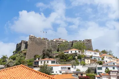 a castle on top of a hill with houses at Quebra Costas I by An Island Apart in Funchal