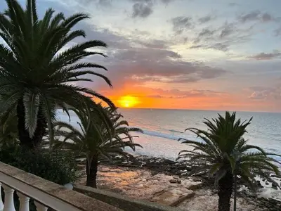a sunset on the beach with palm trees at Luz dream apartment 22G above beach in Luz