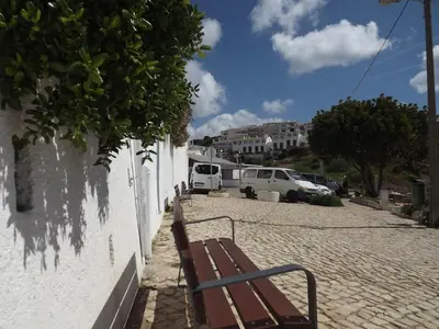 a bench sitting on a brick road next to a wall at Burgau Ocean View Apartment in Burgau