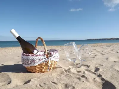 a picnic basket and wine glasses on the beach at Burgau Ocean View Apartment in Burgau