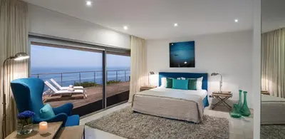 a bedroom with a bed and a balcony with the ocean at Villa Mar Azul in Salema