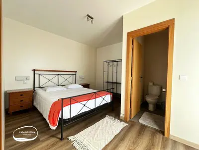 a bedroom with a bed and a bathroom with a toilet at Casa de Pedra AL in Ponta do Pargo