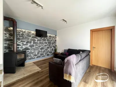 a living room with a couch and a stone wall at Casa de Pedra AL in Ponta do Pargo