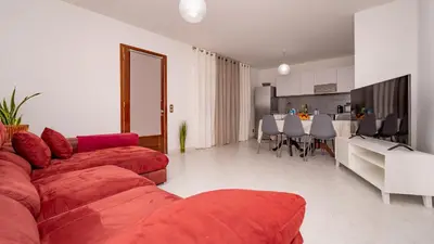 a living room with a red couch and a kitchen at Casa Conceição in Ribeira Brava