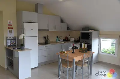 a kitchen with white cabinets and a wooden table at House Vila Santa Ana in Santana