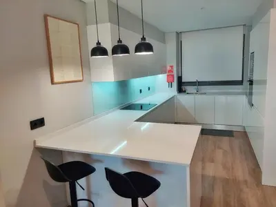 a kitchen with a white counter and two black stools at Funchal Infinito Azul - Moderno elegante com piscina in Funchal