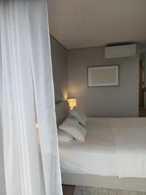 a bedroom with a white bed with a curtain at Funchal Infinito Azul - Moderno elegante com piscina in Funchal
