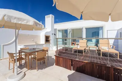 a patio with a table and chairs and an umbrella at Residence Estrela do Mar in Salema