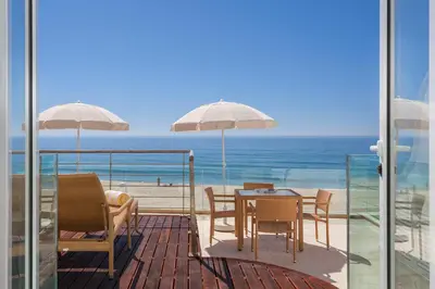 a balcony with a table and chairs and the ocean at Residence Estrela do Mar in Salema
