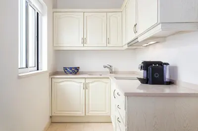 a kitchen with white cabinets and a coffee maker on a counter at Residence Estrela do Mar in Salema