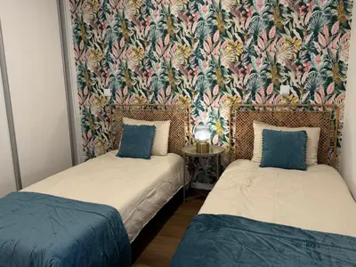 two beds in a room with a floral wallpaper at Stay In Virtudes II in Funchal