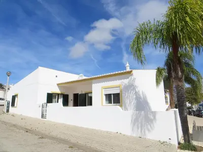 a white house with a palm tree in front of it at 2 minutes walk to the beach Praia da Luz - Casa da Maria in Luz