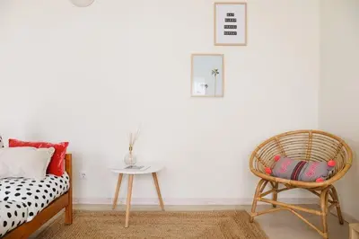 a bedroom with a rattan chair and a table at 2 minutes walk to the beach Praia da Luz - Casa da Maria in Luz