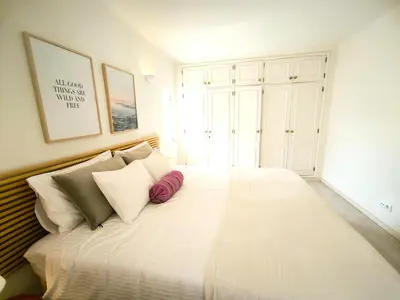 a bedroom with a large white bed with pillows at 2 minutes walk to the beach Praia da Luz - Casa da Maria in Luz