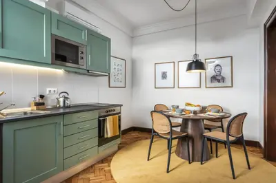 a kitchen with green cabinets and a table with chairs at Zino Apartment A - By Wehost in Funchal