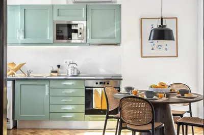 a kitchen with green cabinets and a table with chairs at Zino Apartment A - By Wehost in Funchal