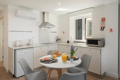 a white kitchen with a table and chairs at OurMadeira - Fort of Old Town Apartments in Funchal